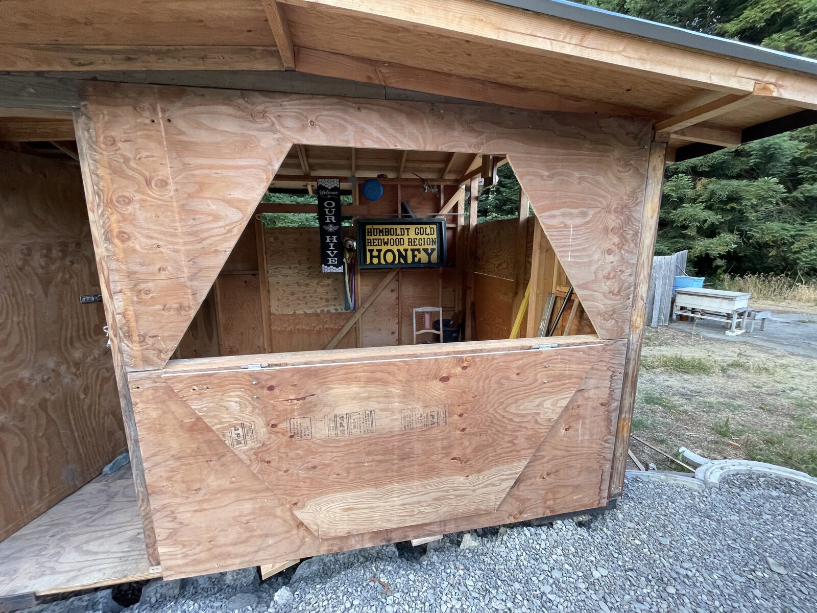 The fold-down plywood counter hinged open with the Humboldt Gold honey sign inside